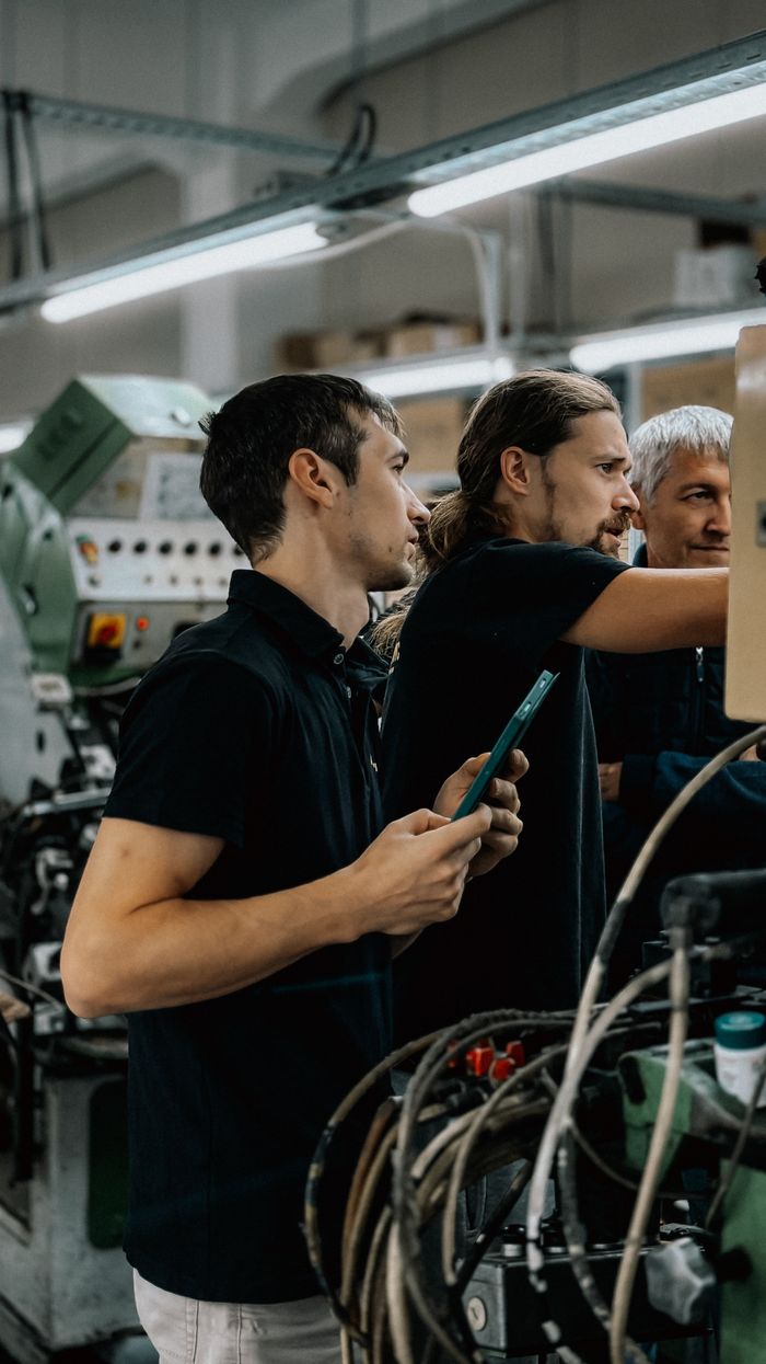 Engineers collaborating in an advanced manufacturing facility, focusing on machinery operations.